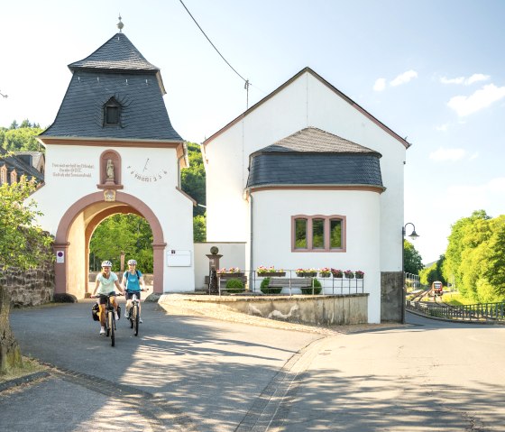 Radfahrer auf dem Kyll Radweg vor dem Tor vom Kloster St. Thomas, © Eifel Tourismus GmbH